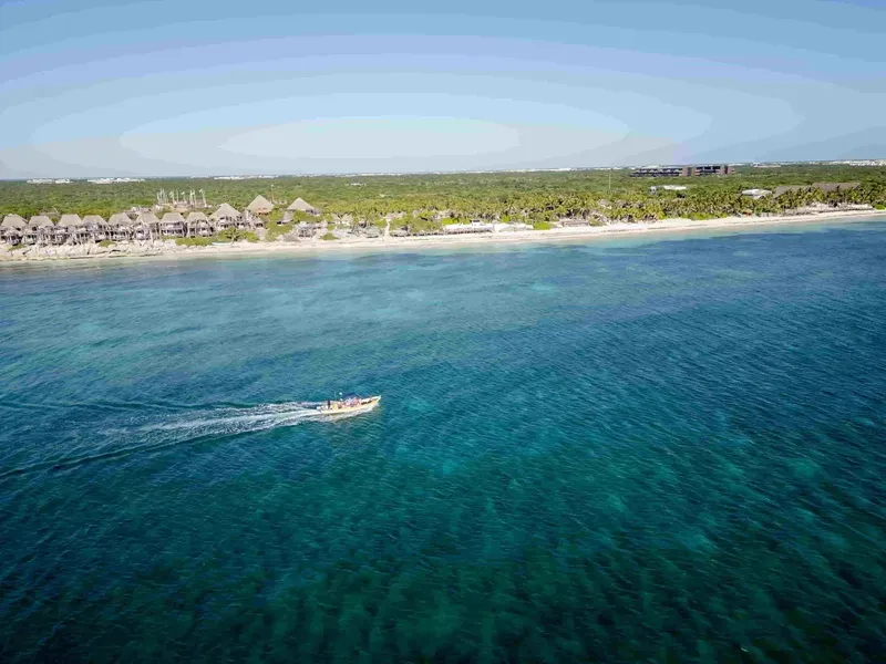 Bateau de plongée naviguant sur une mer turquoise près d'une plage