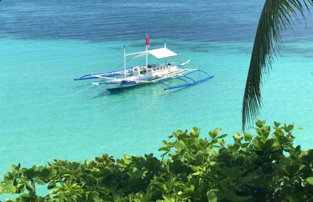 Bateau traditionnel à balanciers sur une eau turquoise et claire