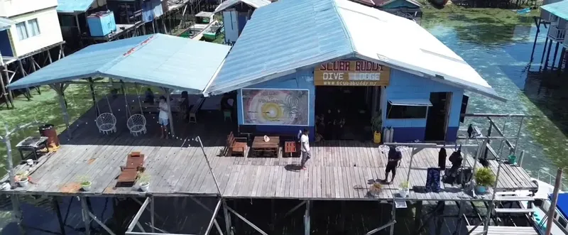 Centre de plongée sur pilotis avec des personnes se relaxant et du matériel