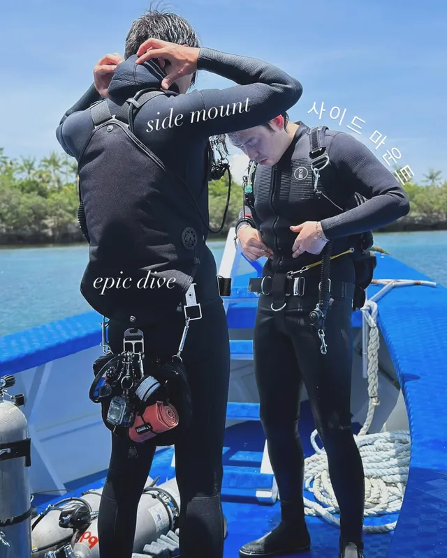 Deux plongeurs en combinaison se préparent à bord d'un bateau