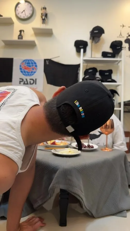 Homme mangeant à table devant des casquettes et du matériel