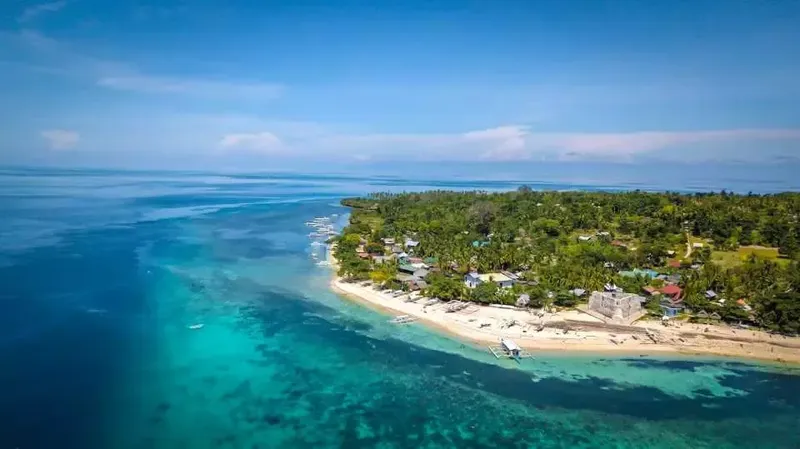 Vue aérienne d'une plage tropicale avec des bateaux et végétation luxuriante