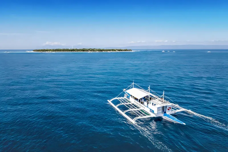 Bateau de plongée blanc et bleu navigue sur une mer turquoise