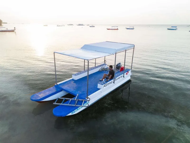 Bateau de plongée bleu avec passagers sur une mer calme