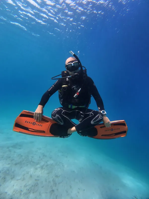 Plongeur en combinaison noire nageant avec des palmes orange sous l'eau