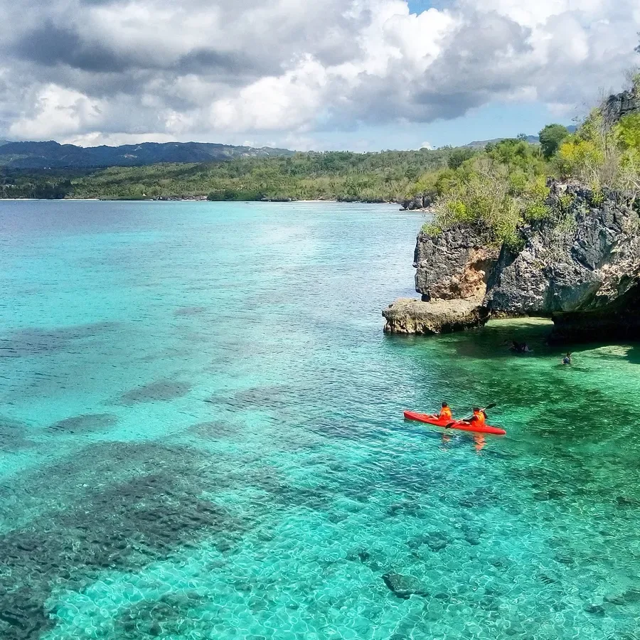 Kayak rouge sur une eau turquoise claire avec des falaises rocheuses