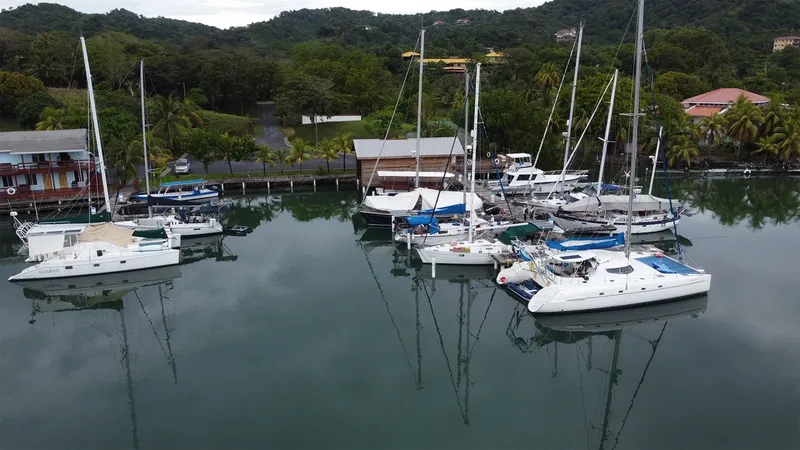 Plusieurs voiliers et catamarans amarrés dans un port tropical calme