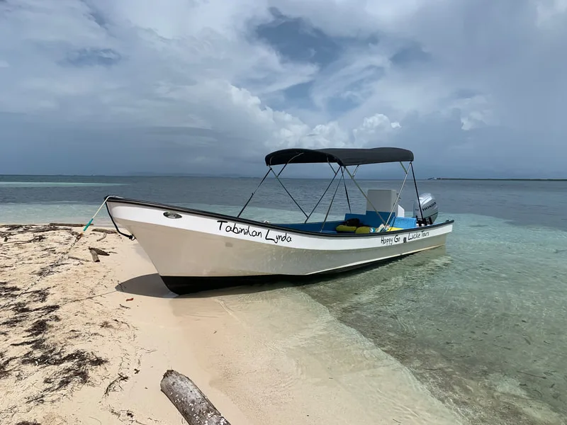 Bateau blanc échoué sur une plage de sable clair sous un ciel nuageux