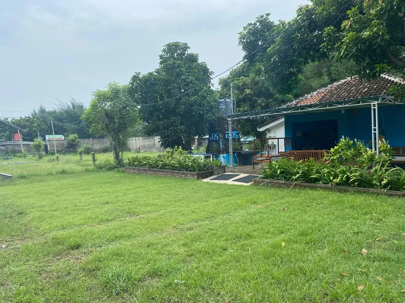 Petite maison bleue avec toit en tuiles, entourée de verdure et d'arbres