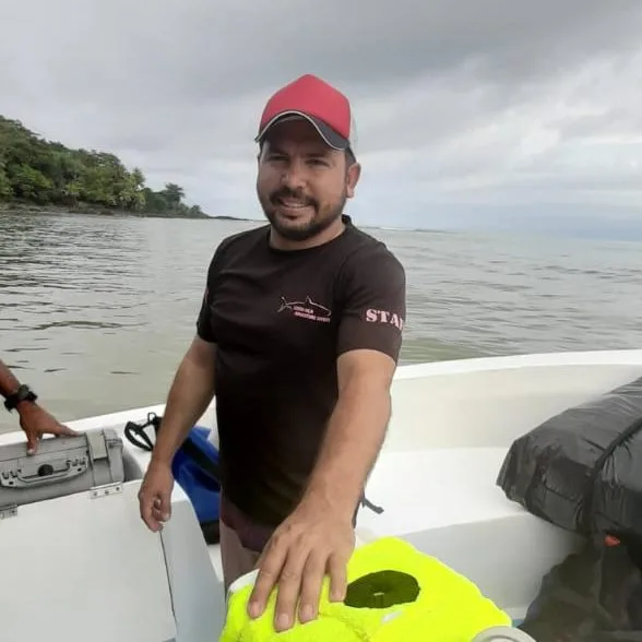 Homme souriant sur un bateau blanc, prêt pour une sortie en mer