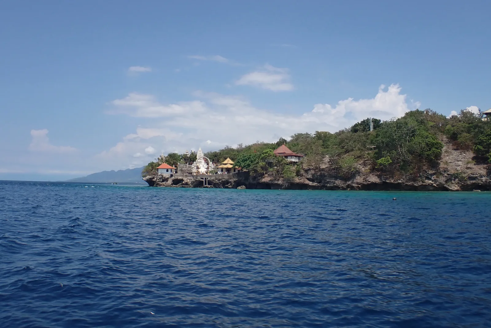 Côte rocheuse avec bâtiments et végétation luxuriante face à la mer