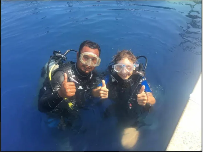 Deux plongeurs souriants font un signe de pouce levé sous l'eau