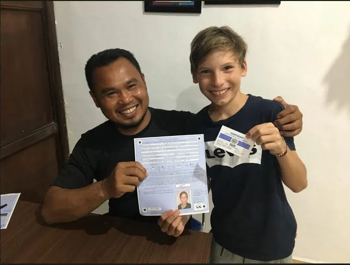 Deux hommes souriants présentent un certificat de plongée et une carte