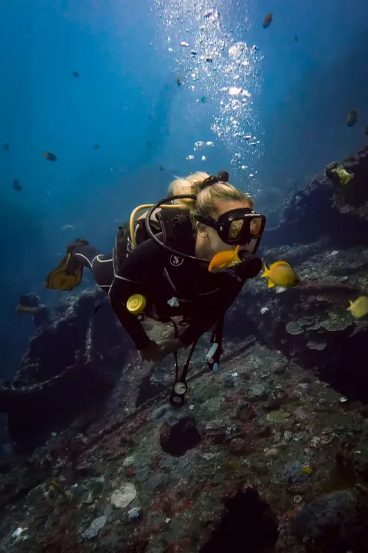 Plongeuse souriante interagissant avec des poissons dans un récif corallien