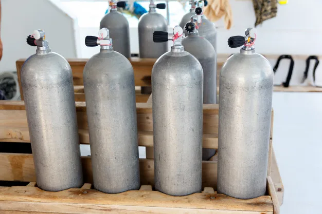 Bouteilles de plongée en aluminium alignées sur un support en bois