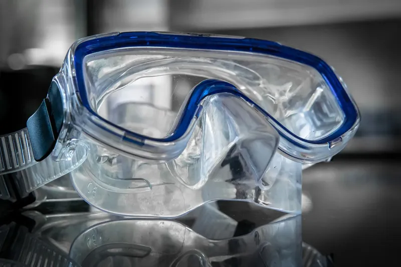 Masque de plongée transparent avec joint bleu sur surface sombre