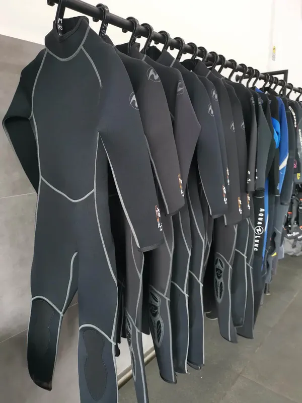 Rangée de combinaisons de plongée noires et bleues suspendues sur cintres