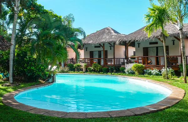 Piscine turquoise entourée de végétation luxuriante et bâtiments tropicaux