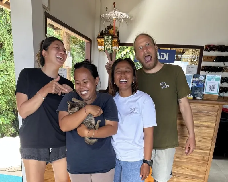 Quatre personnes souriantes posent devant un décor tropical et coloré