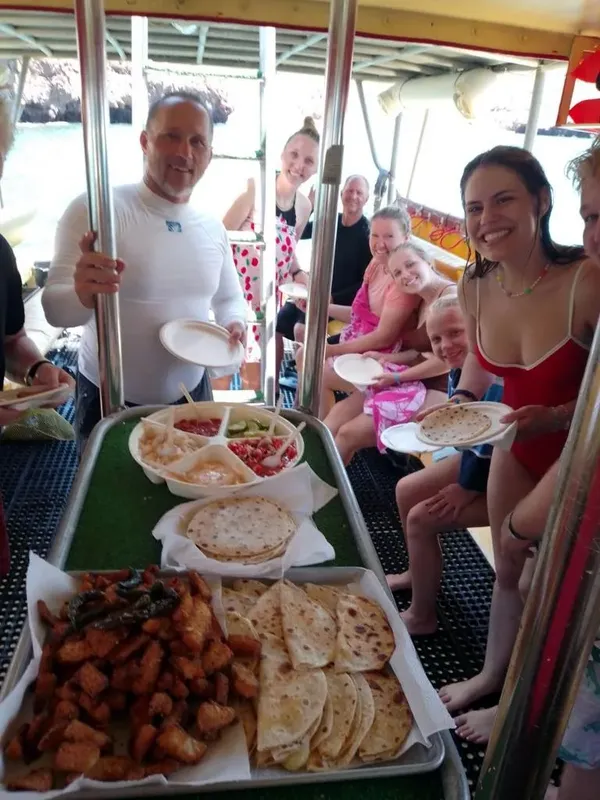 Groupe de personnes souriantes sur un bateau avec de la nourriture