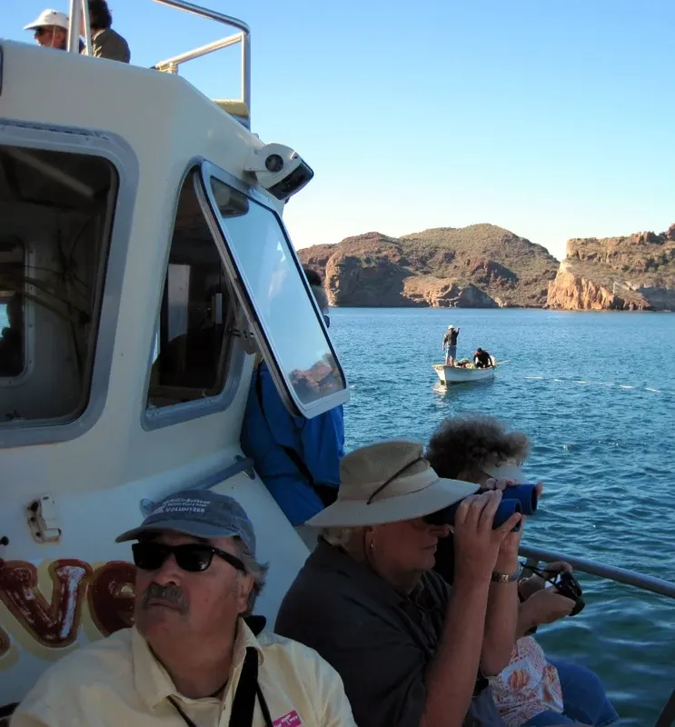 Personnes observant la mer depuis un bateau, paysage côtier en arrière-plan