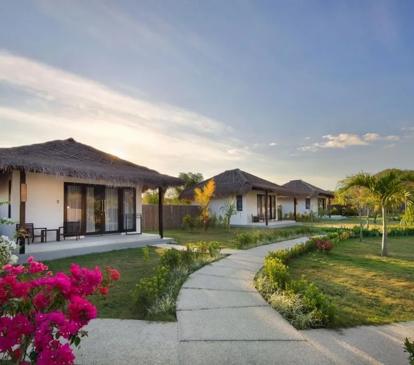 Petits bungalows blancs avec toits de chaume et jardin tropical