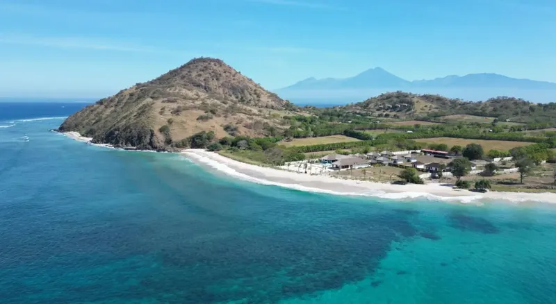 Vue aérienne d'une plage, d'un centre et de collines verdoyantes