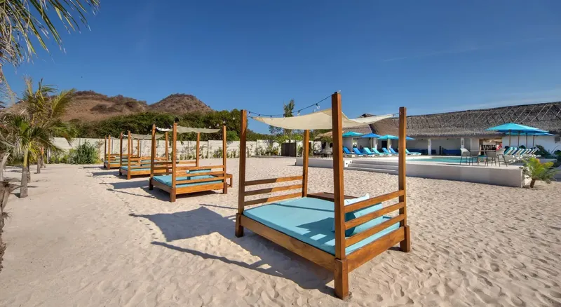 Plage de sable blanc avec des lits de soleil et une piscine