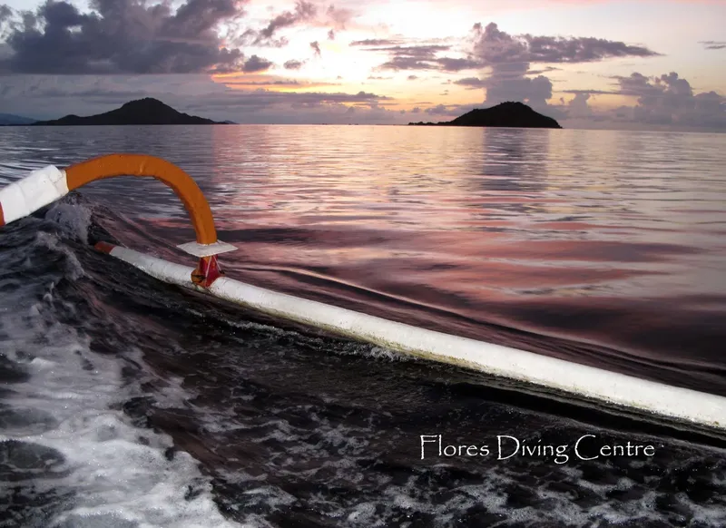 Bateau de plongée en mer au coucher du soleil avec îles au loin