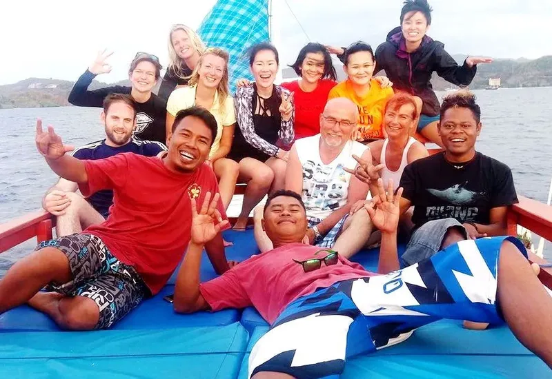 Groupe de personnes souriantes sur un bateau bleu en mer