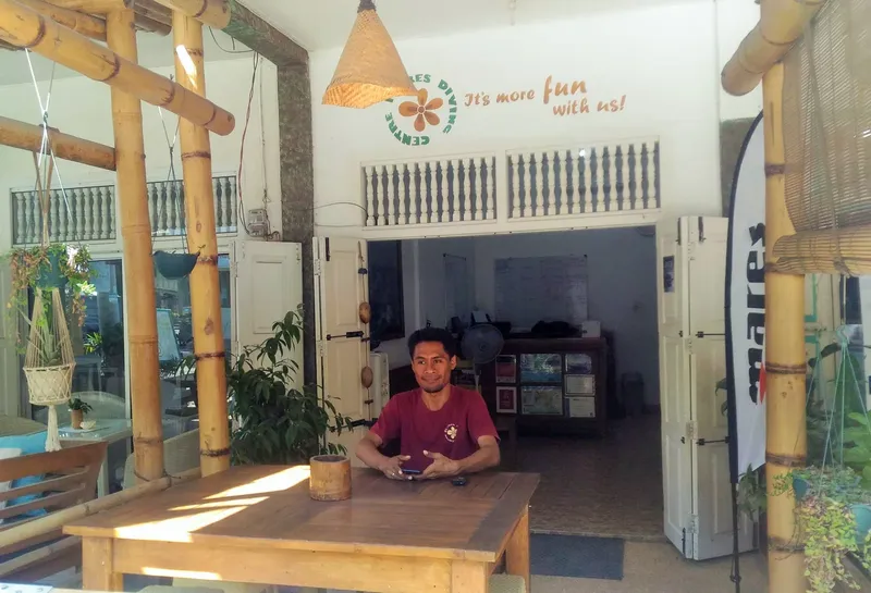 Un homme assis à une table devant l'entrée d'un centre de plongée