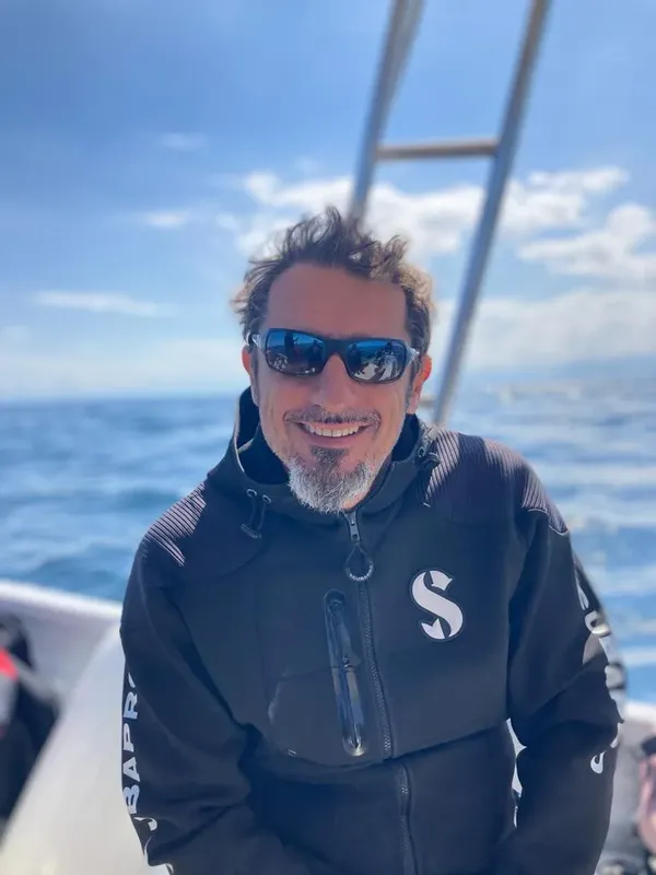 Homme souriant portant des lunettes de soleil sur un bateau en mer