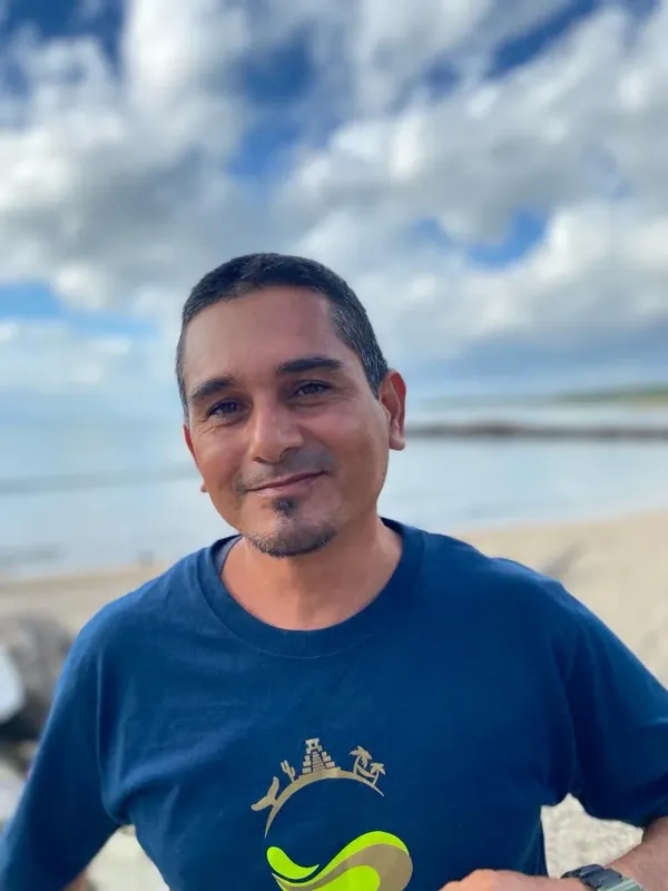 Portrait d'un homme souriant devant un ciel nuageux et la mer