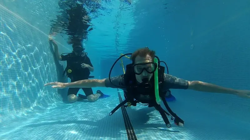 Deux plongeurs s'entrainent en piscine, un en premier plan, l'autre derrière
