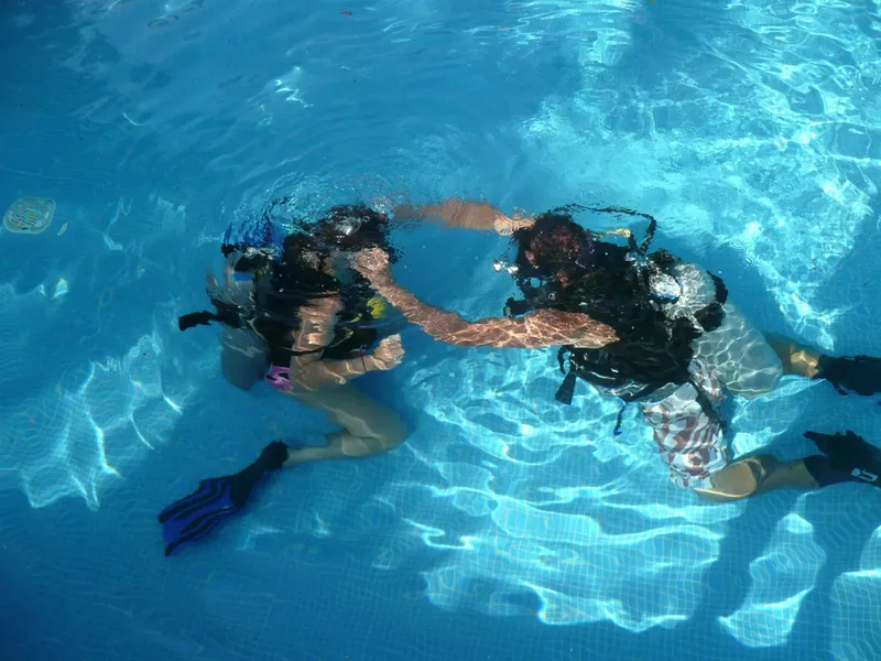 Deux plongeurs s'entraînent en piscine, équipement complet, eau claire
