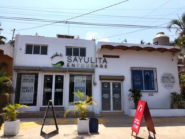 Façade d'un centre de plongée avec des affiches et plantes tropicales