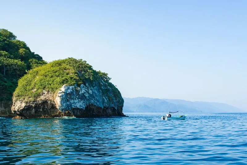 Petit bateau avec des plongeurs près d'une île verdoyante en mer