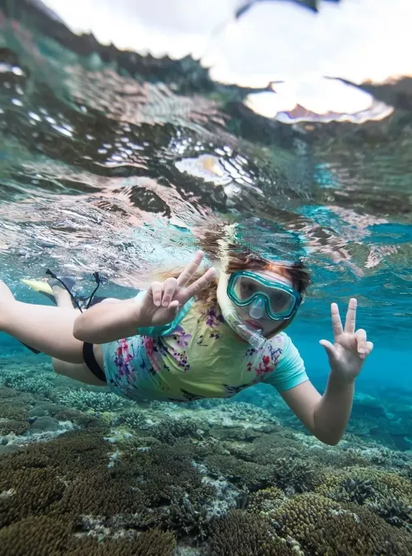 Plongeuse souriante avec signe de la paix sous l'eau turquoise