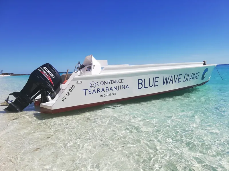 Bateau de plongée blanc et rouge amarré sur une plage de sable clair