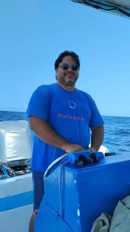 Homme souriant portant un t-shirt bleu sur un bateau en mer