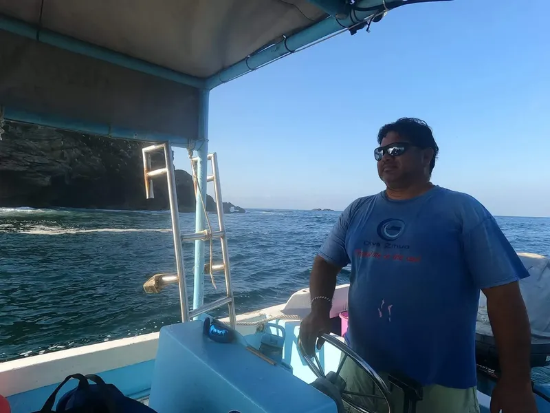 Homme au volant d'un bateau de plongée en mer, ciel bleu