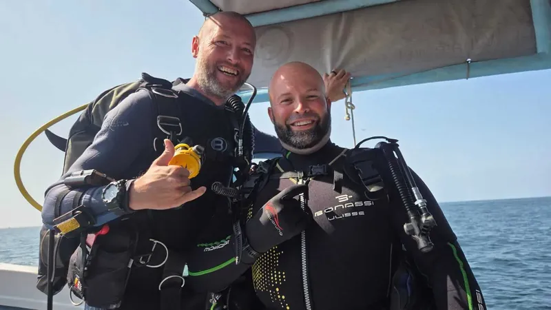 Deux plongeurs souriants en combinaison sur un bateau en mer