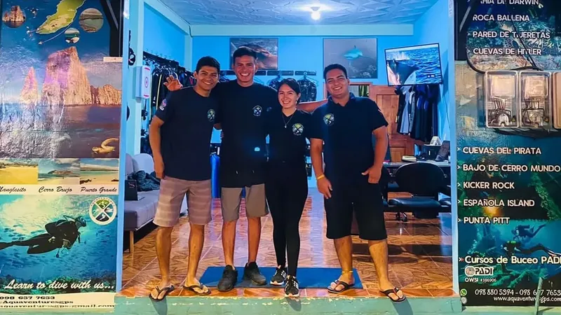 Quatre personnes souriantes posent devant l'intérieur d'un centre de plongée