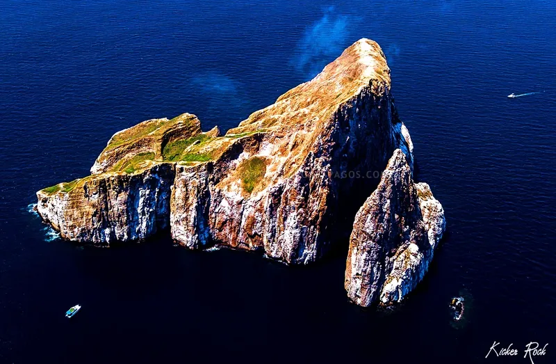 Île rocheuse isolée en mer bleue avec quelques bateaux à proximité
