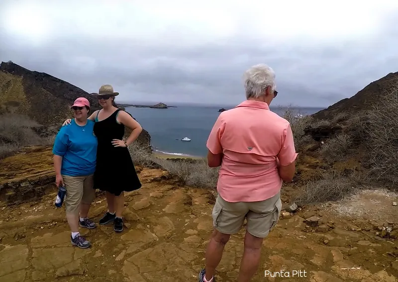 Trois personnes se tiennent debout sur une colline rocheuse avec vue sur la mer