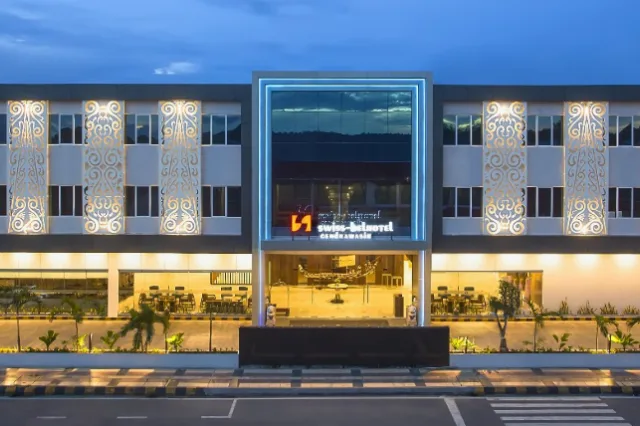 Façade d'un bâtiment moderne avec enseigne lumineuse et végétation tropicale