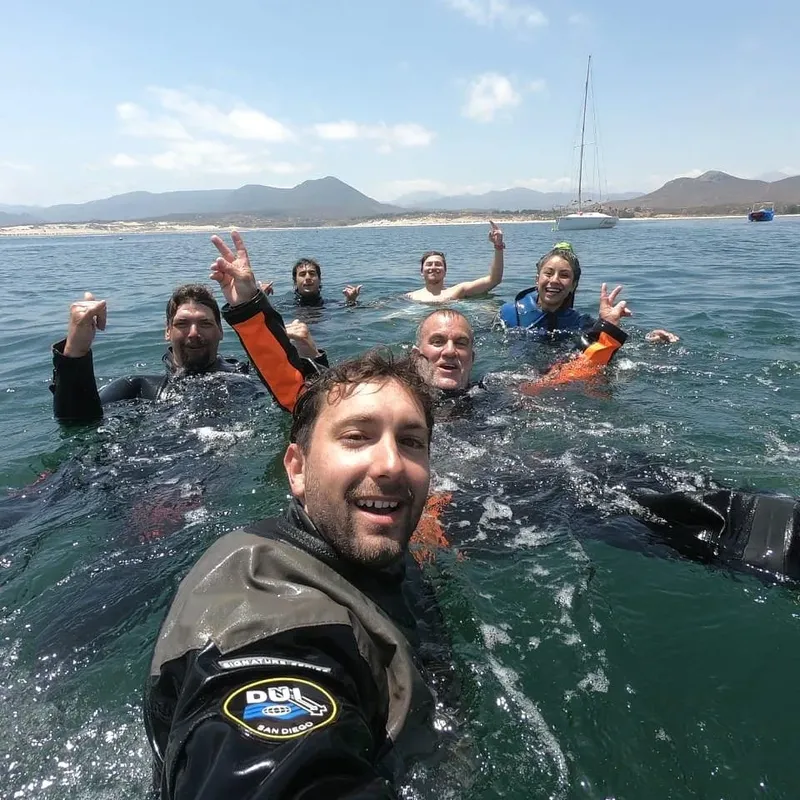 Groupe de plongeurs souriants dans l'eau, ciel bleu en arrière-plan