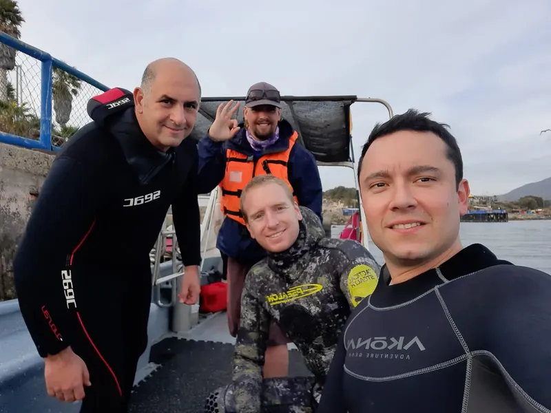 Quatre plongeurs souriants posent sur un bateau en mer