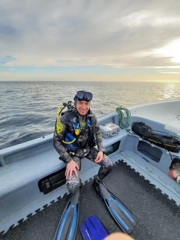 Plongeur souriant équipé à bord d'un bateau en mer calme