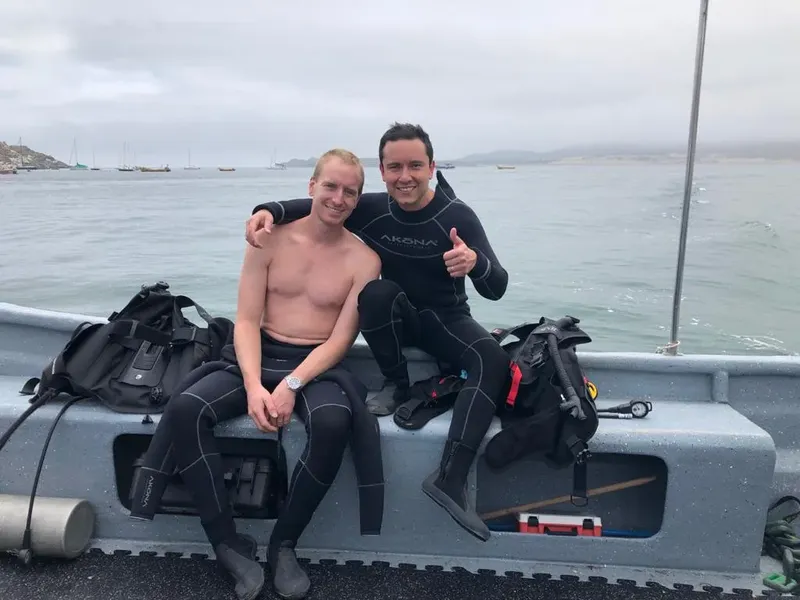 Deux plongeurs souriants assis sur un bateau avec leur équipement